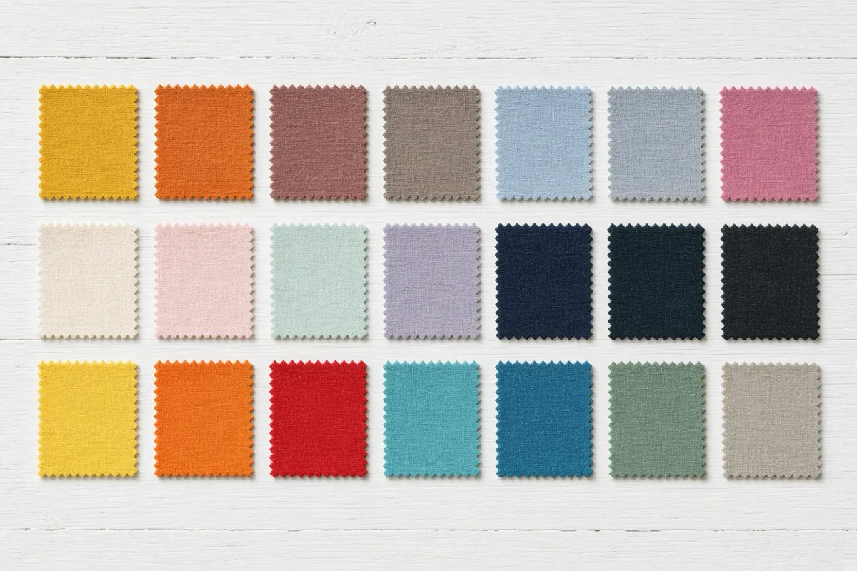 Flat-lay of fabric swatches in three rows on a white table: the top row grades from warm to cool, the middle from light to deep, the bottom from bright to muted.